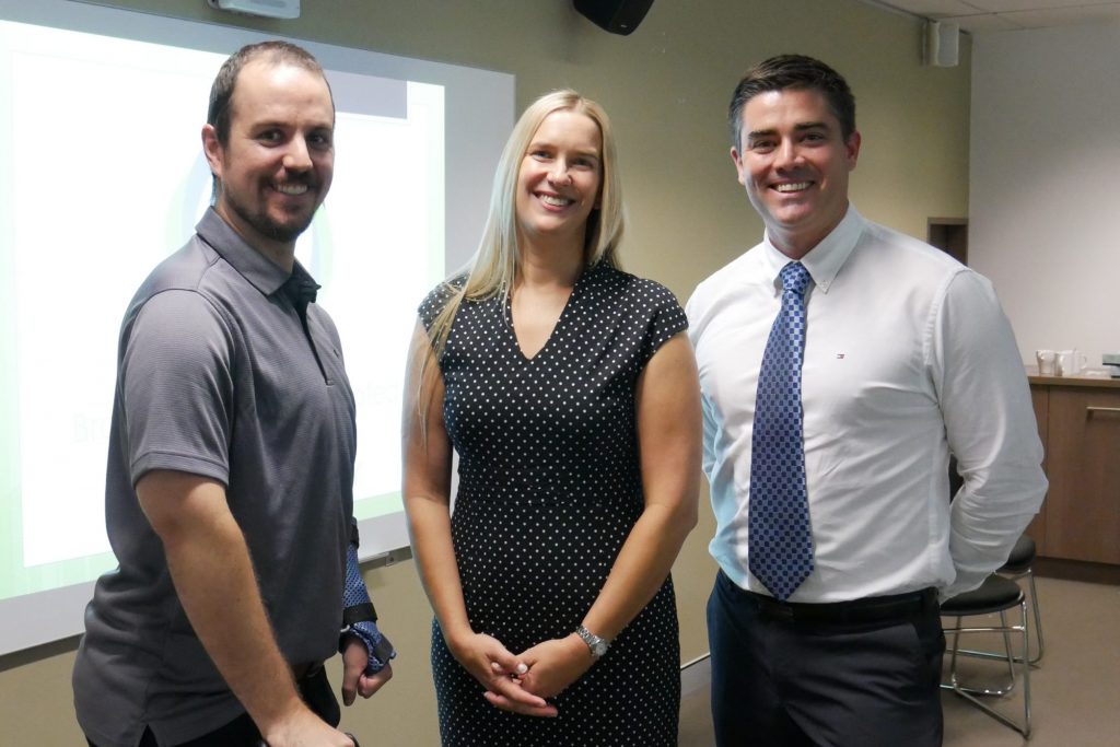 Three people standing in front of presentation screen