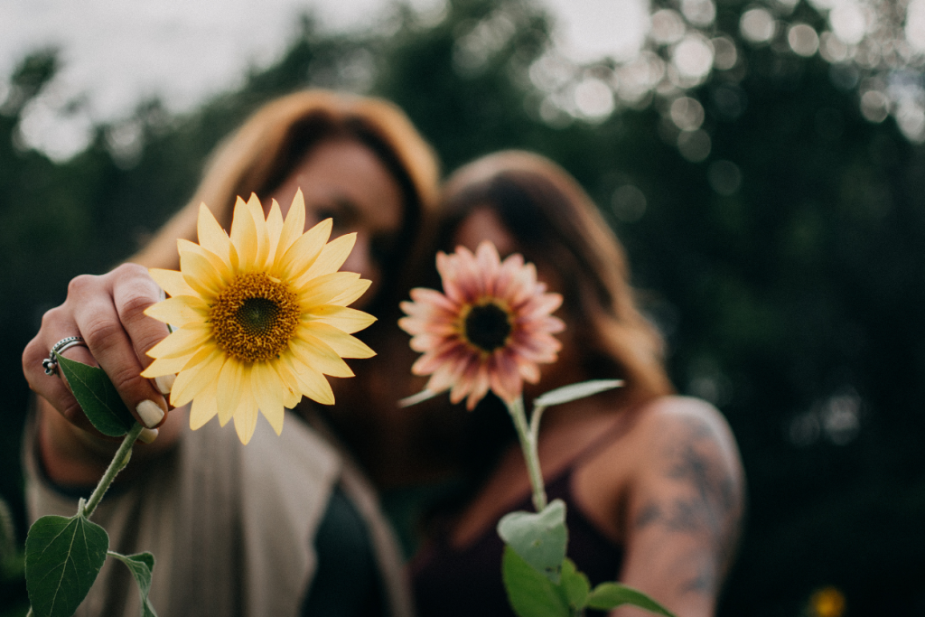 Two woman holding up flowers