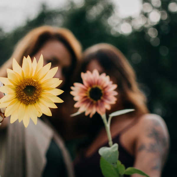 Two woman holding up flowers