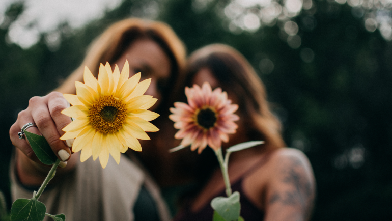 Two woman holding up flowers